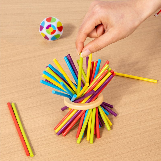 Hand pulling a yellow stick from a colorful wooden balancing game, featuring fun and educational Montessori toys.