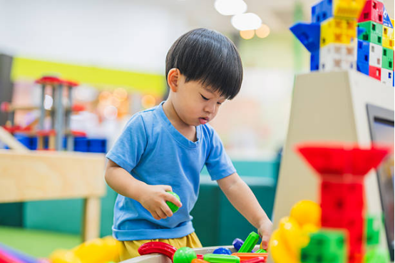 A young boy playing with colorful building blocks and magnets, exploring creative Montessori toys in a playroom.
