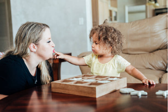 A child touches their mother's lips while playing with Montessori toys.