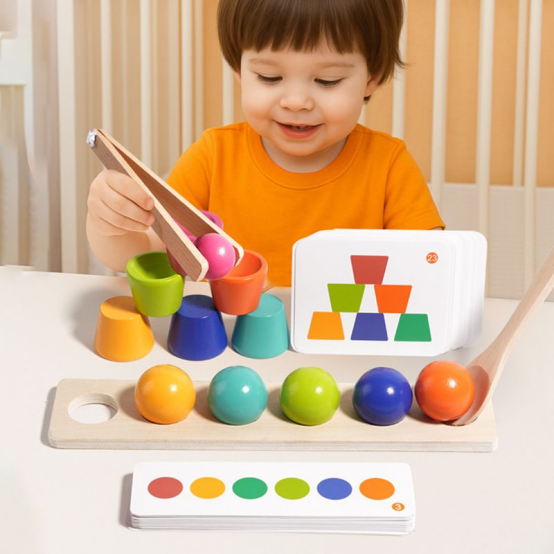 A child practicing fine motor skills with wooden Montessori toys using tongs to sort colorful balls into cups.