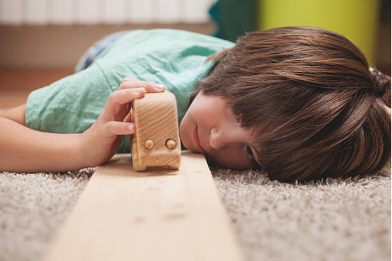 Young boy playing with a wooden car on a ramp, a classic example of engaging Montessori toys for toddlers.