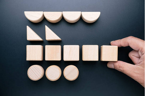 Hands organizing geometric wooden blocks, showcasing how Montessori toys teach shapes and sorting skills.