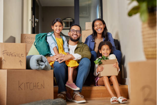 A happy family moving into a new home with boxes, ready to set up a playroom with educational Montessori toys.