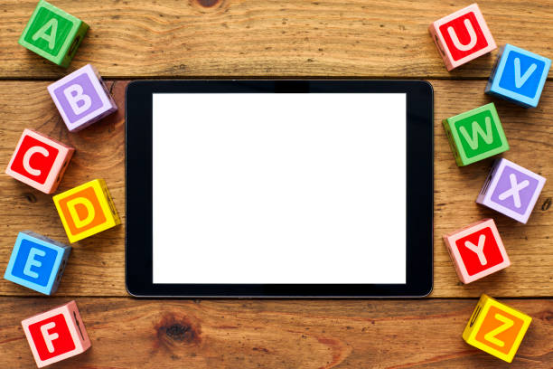 Tablet surrounded by alphabet blocks, demonstrating digital learning tools paired with Montessori toys.