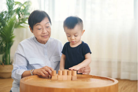A grandmother and toddler stacking natural wooden blocks, using Montessori toys for cognitive development.