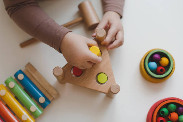 Child's hands playing with colorful wooden Montessori toys and a peg puzzle.