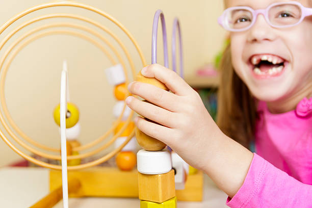 Happy child plays with wooden bead maze, an engaging Montessori toy.