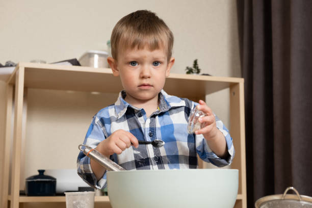 Young boy learning practical life skills with Montessori toys, measuring ingredients.