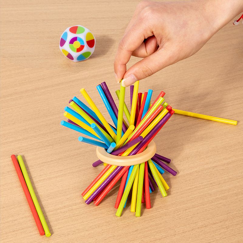 Hand playing with colorful stick balance game, engaging with Montessori toys.