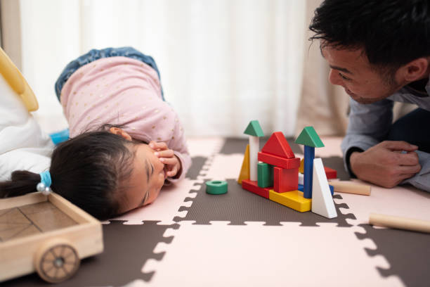 Father and baby playing with colorful wooden building block Montessori toys on the floor.